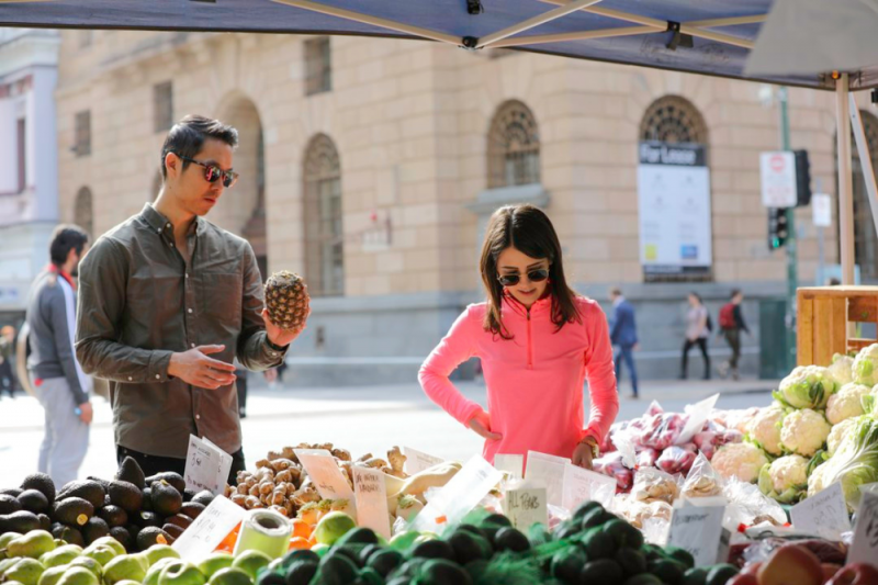A young man and woman shopping for fruit and vegetables at the farmer's market