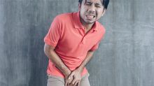 A man with a pained expression holding his testicles with both hands