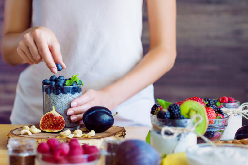 A young woman prepares a drink with yoghurt, chia and blueberries - all good for gut health