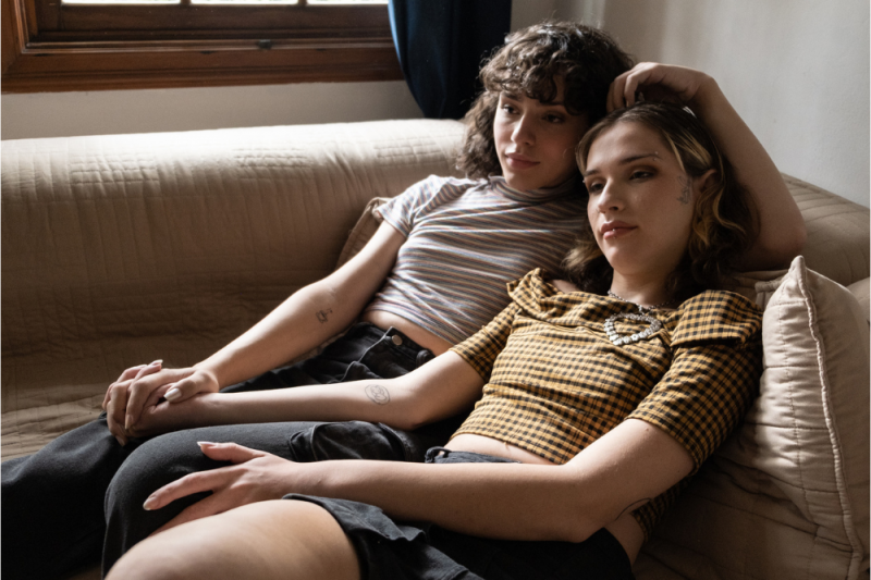 A couple lie on a couch holding hands