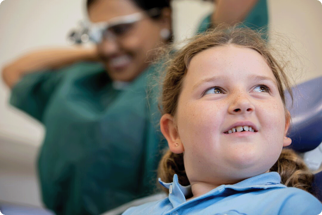 A young girl seated in a dental chair, looking calm and prepared for her dental appointment.