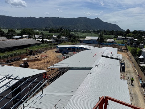 Construction site with scaffolding and rooftops in the foreground and tree-covered mountain range in the background
