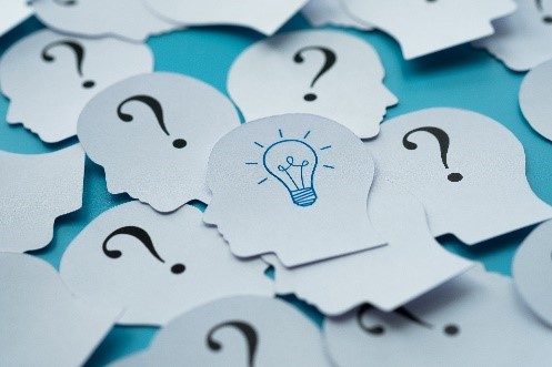 picture of little paper head silhouettes with question marks and light bulbs on them