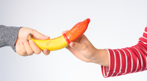 People putting a condom on a banana.