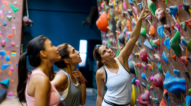 Three young woman looking at the routes on an indoor rock climbing wall