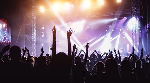 A crowd at a music concert raise their hands up into the light