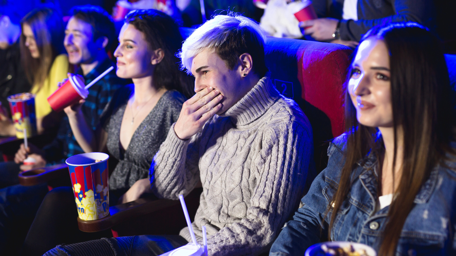 A photo of teenagers in a movie theatre drinking soft drink