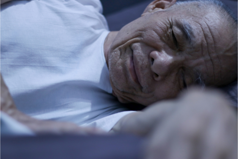 A mature man fast asleep in bed