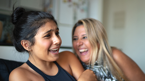 Mother and daughter laughing on a couch