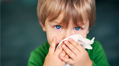 A young boy with RSV cleans his nose with a tissue