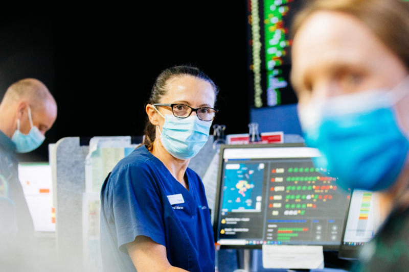 A Queensland Health registered nurse in front of the large digital screens of the patient access coordination hub (PACH) at the Princess Alexandra Hospital