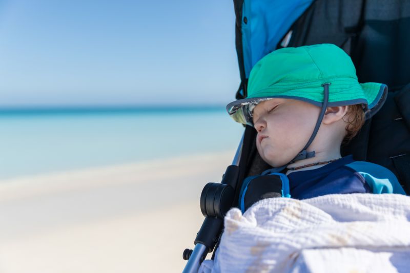 Baby sleeping in pram at the beach