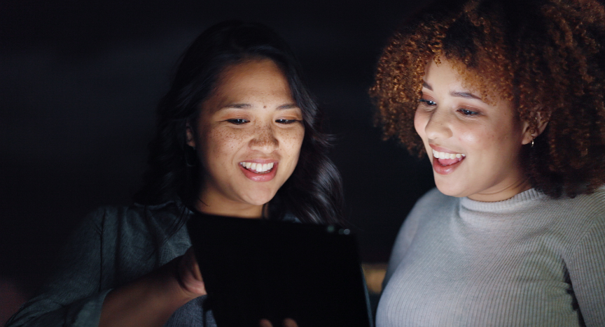 A group of teenagers huddle around a computer.