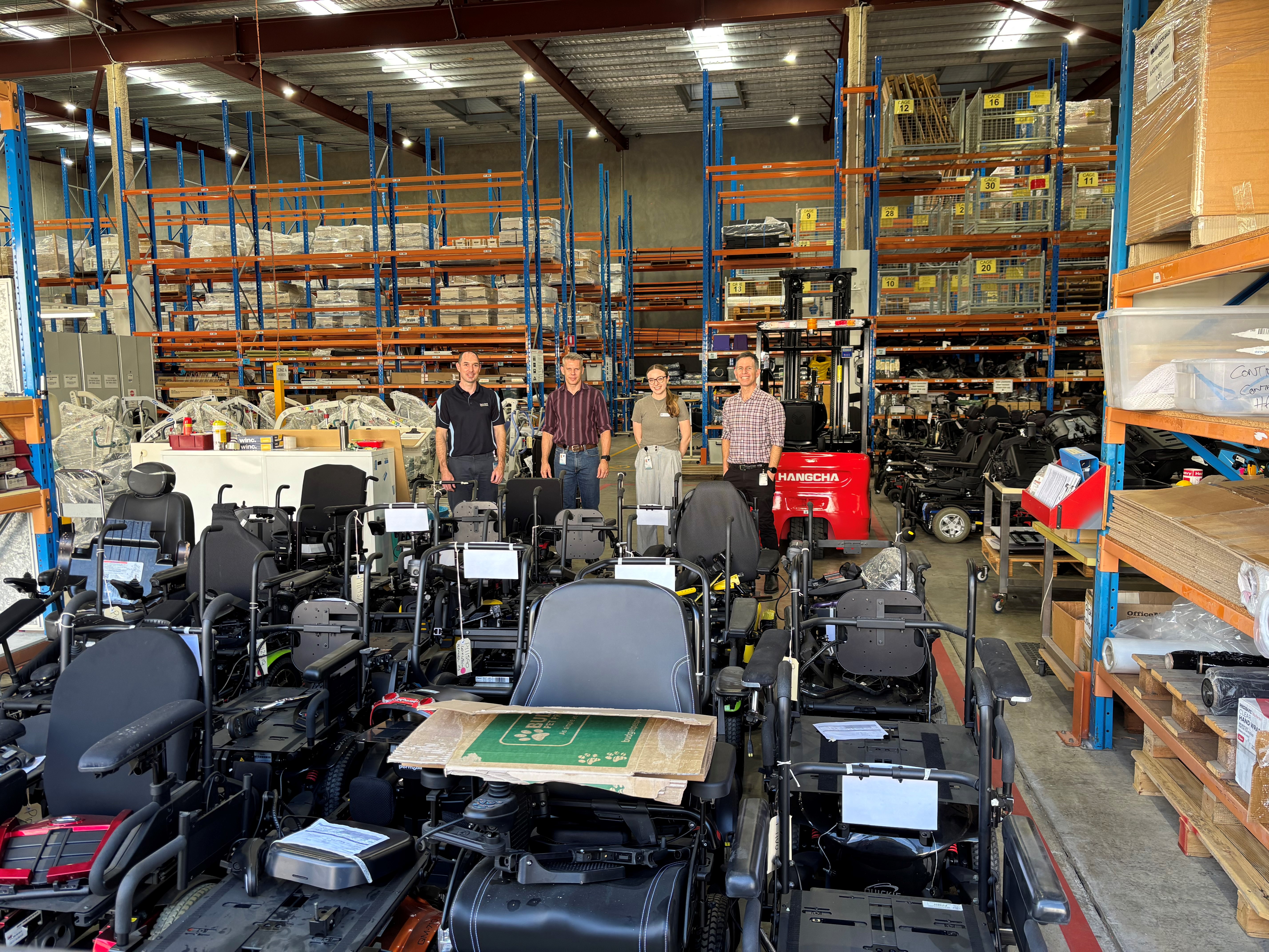 Photograph of James, Nick, Annie and Mick with MASS stock devices in front of them standing in the MASS Warehouse.