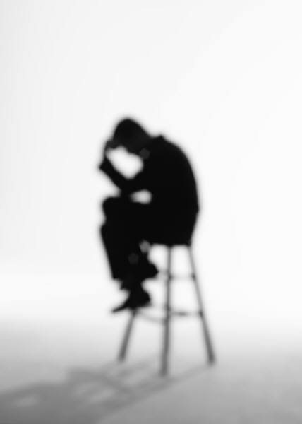 silhouette of a man sitting on a stool thinking