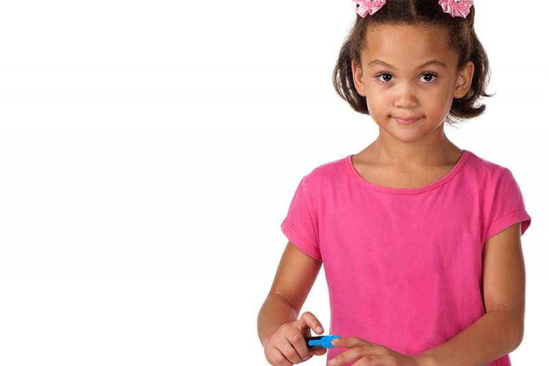 A young diabetic girl in a pink dress with pink flower hairclips checks her blood sugar levels