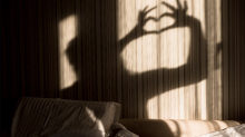 A person's shadow making a heart shape with their hands