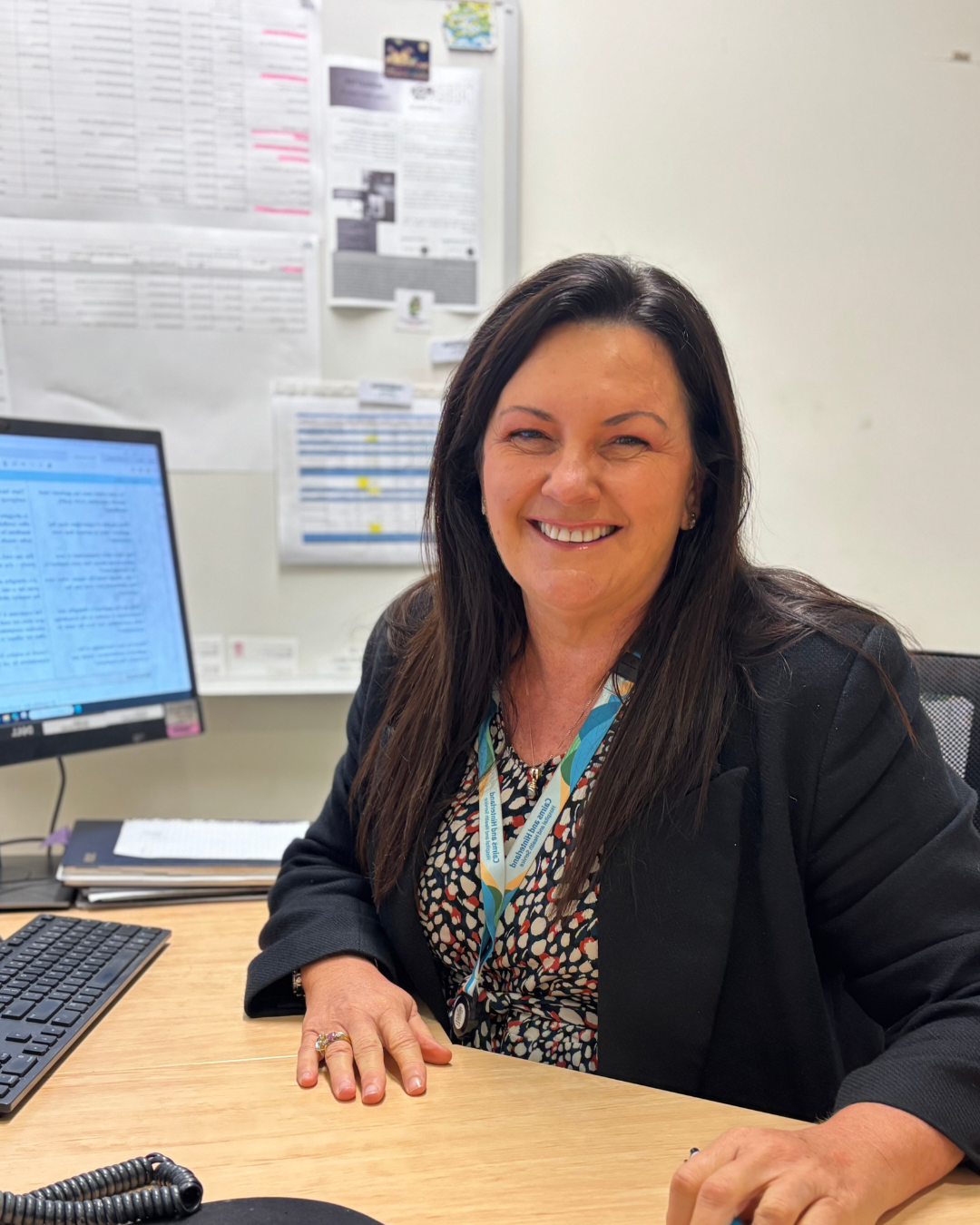 A woman is sitting at her desk smiling