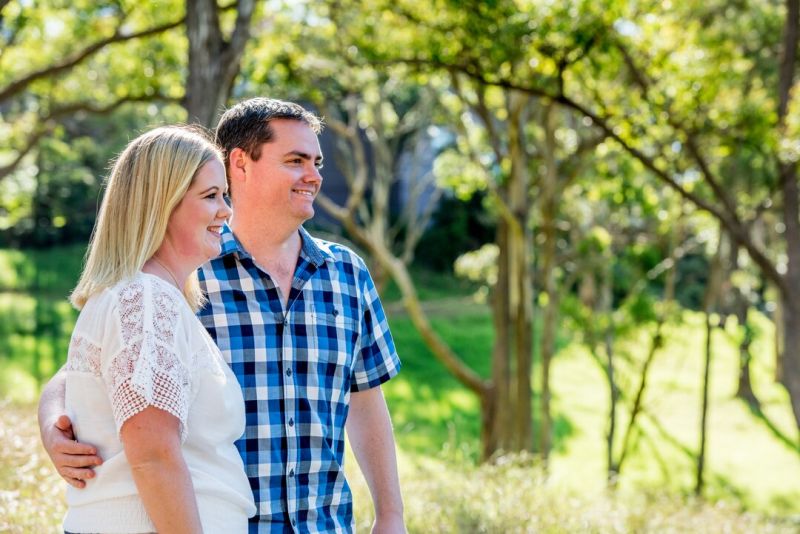 A smiling young couple walking arm in arm in a forest