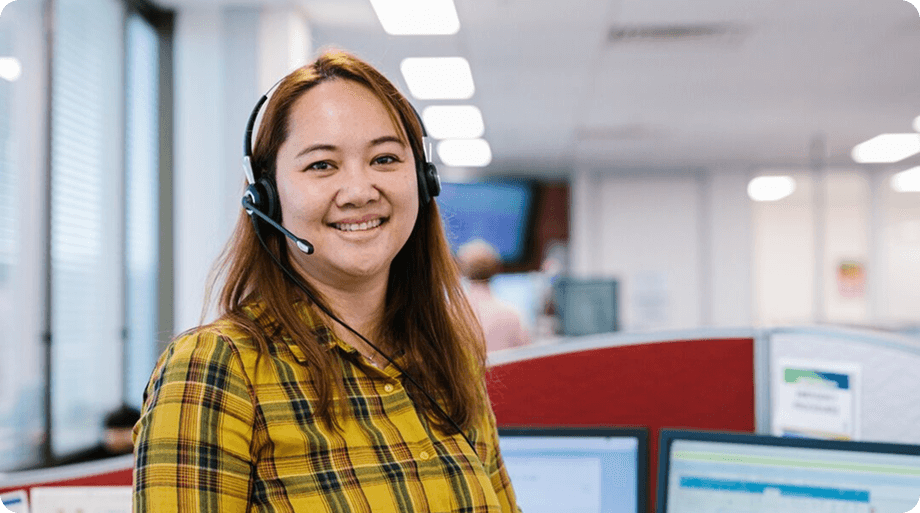 Smiling female nurse wearing a headset in a call center office.