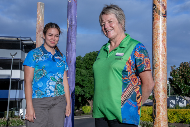 A senior indigenous midwife and trainee health practitioner from the Boomagam Caring Indigenous Maternity Team, Darling Downs Hospital and Health Service smile at the camera outdoors