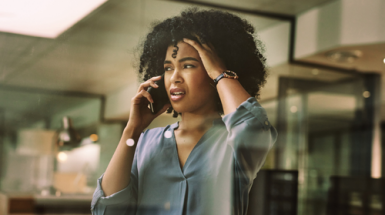 A young business woman on a mobile phone call looks anxious and panicked
