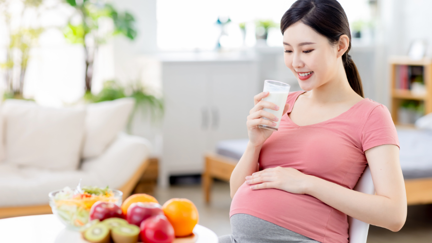 A pregnant woman drinks a glass of milk.