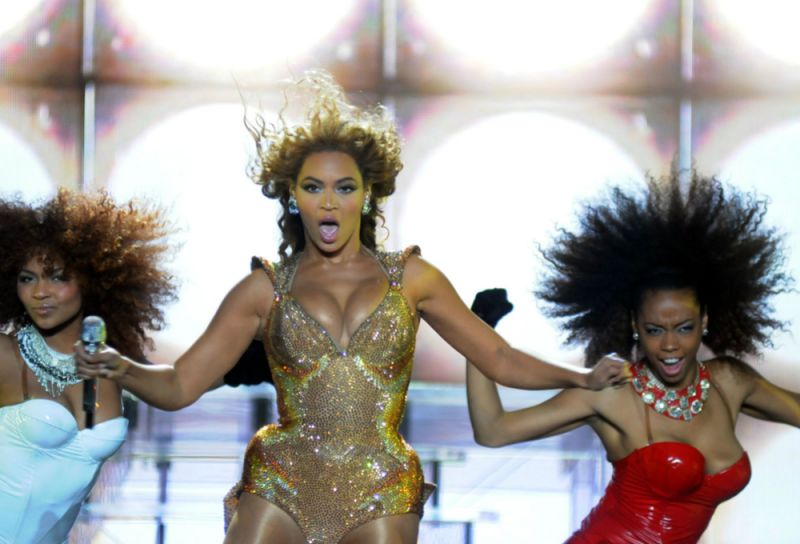 On stage, Beyonce sings in front of two back up dancers.