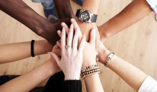 A group of Professionals clasping hands in a show of support