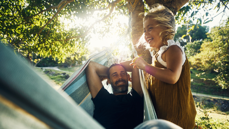 A young girl swings her father in a hammock