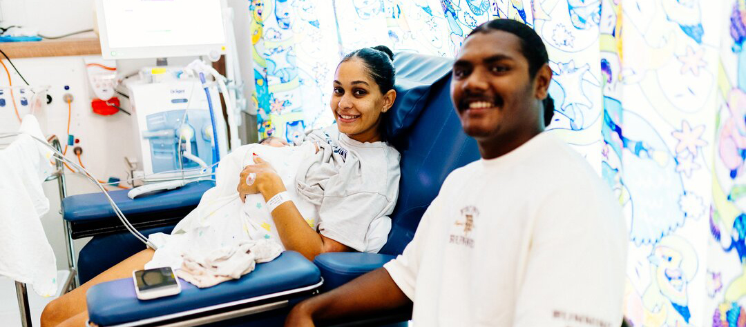 A man and woman sitting together in a hospital bed, both appearing calm and supportive of each other.