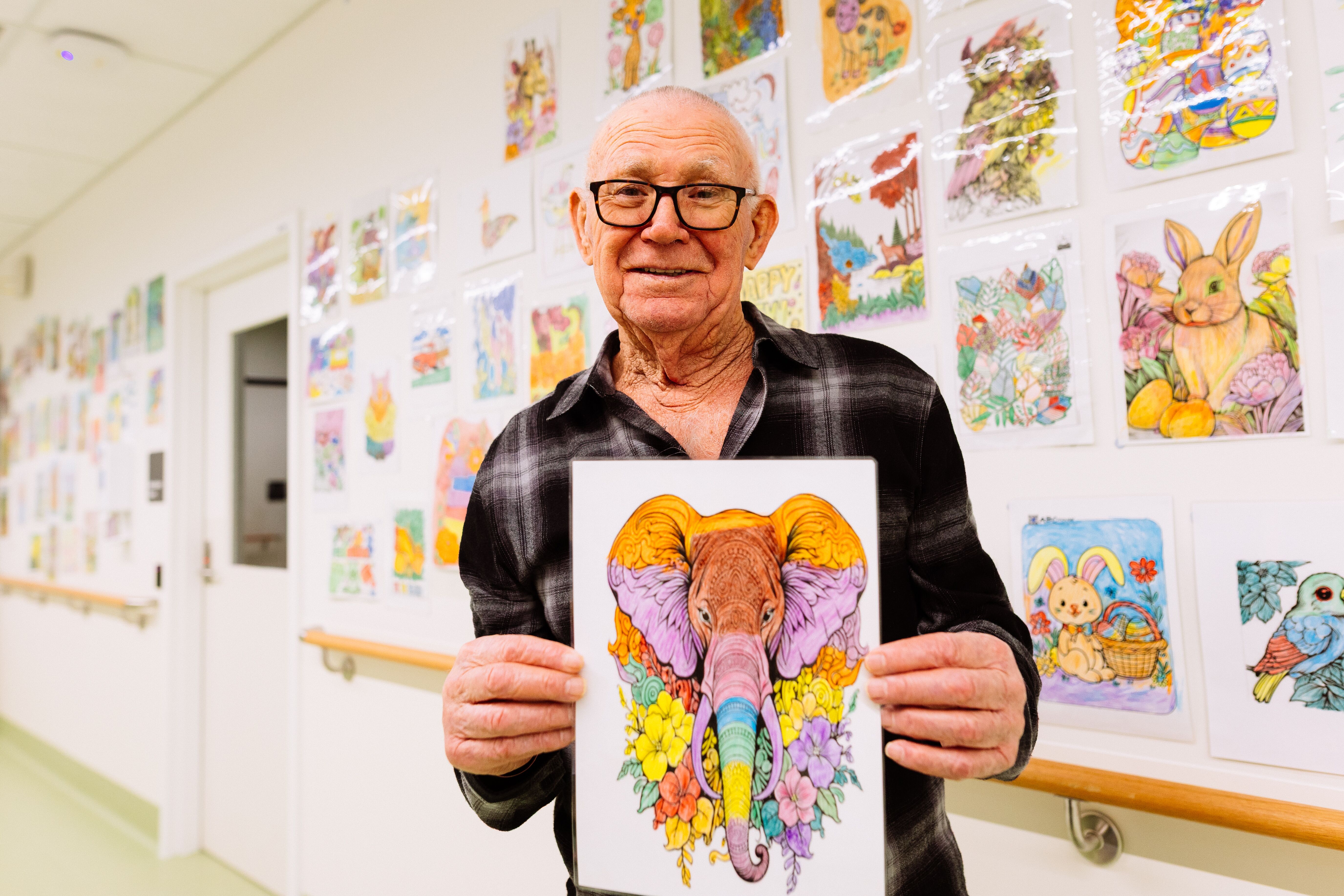 A patient in the Logan Acute Cognitive Unit smiles as he shows his artwork he has completed at the unit.